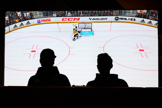 Två personer spelare NHL 23 innan ishockeymatchen i SHL