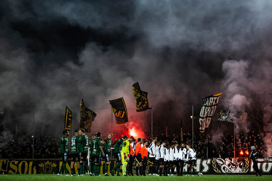 Varbergs och AIKs spelare framför supportar med bengaliska