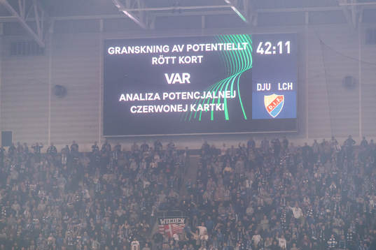 A big screen displays a VAR review message