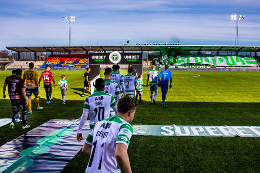 Örgrytes och Västerås spelare med supportrarnas tifon i