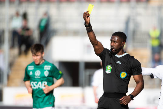 Domare Fredrik Oppong delar ut ett gult kort