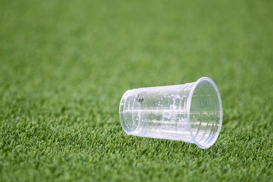 En plastmugg ligger på konstgräset
