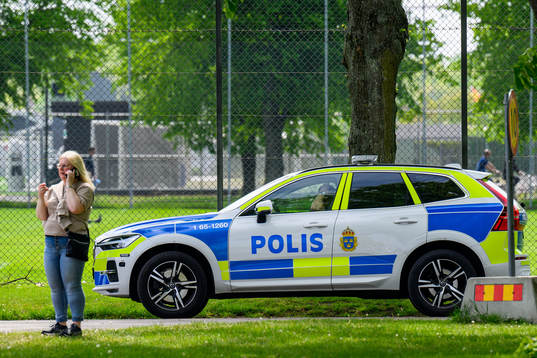 En kvinna pratar i telefon bredvid en polisbil