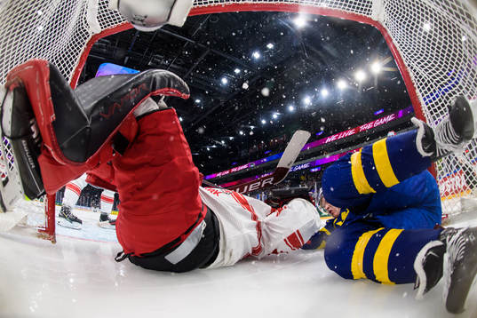 Jonatan Berggren of Sweden (R) crashes onto goaltender