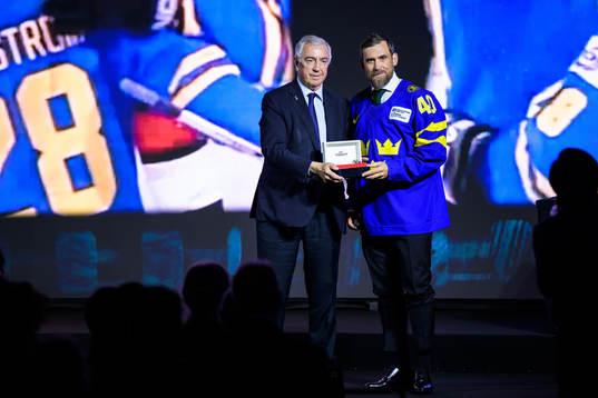 Luc Tardif, president of the IIHF, hands over a watch to