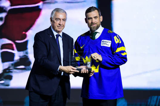 Luc Tardif, president of the IIHF, hands over a trophy to