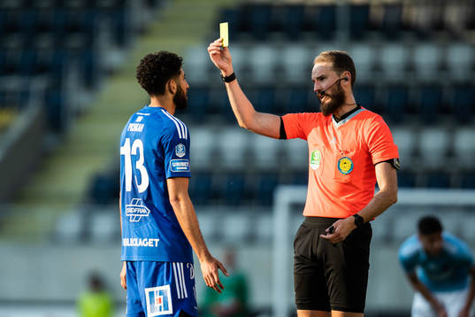 Domare Andreas Dufva-Johansson delar ut ett gult kort till