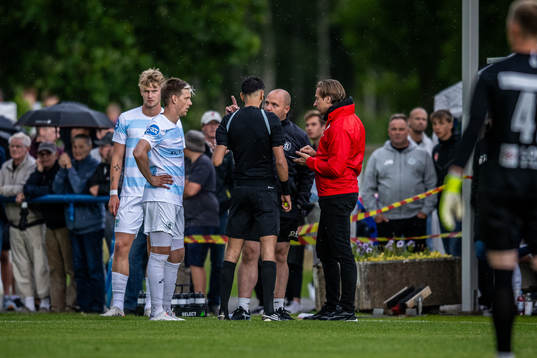 Matchfunktionär i samtal med domare och lagansvariga på