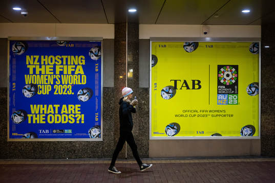 A woman walks past signs with adds about the FIFA Women's