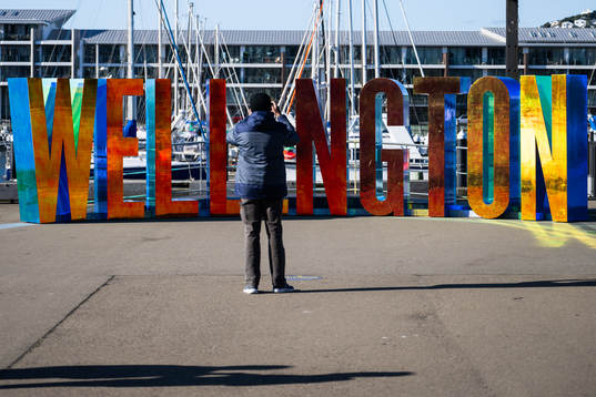 A man photographs letters spelling ”Wellington”