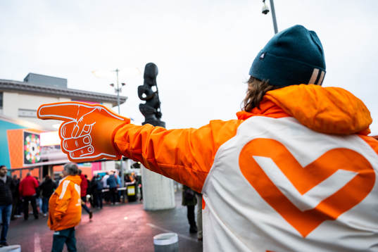 A volunteer points directions for spectators outside the