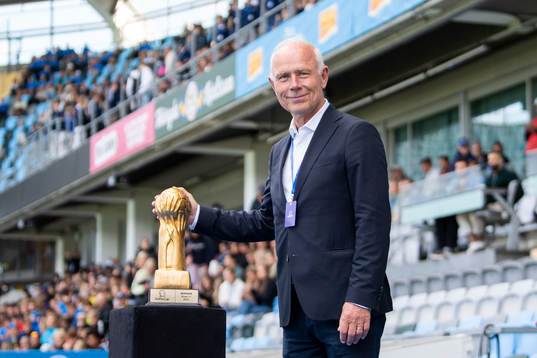 Prisutdelare Dennis Andersson poserar med en pokal