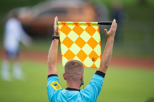 Assisterande domaren signalerar för byte I matchen i div.