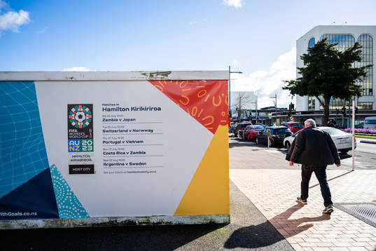 A man walks past barriers with the logo for the FIFA