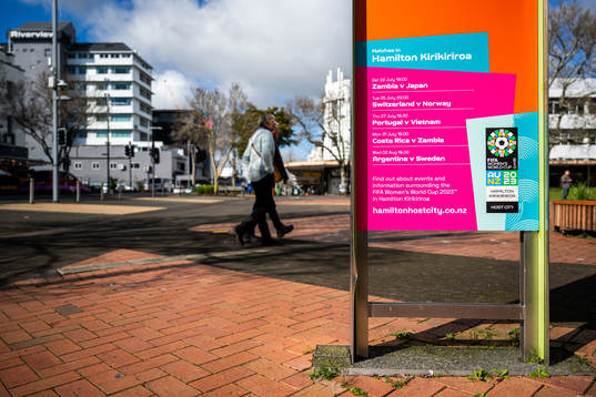 A couple walk past a sign with the logo for the FIFA