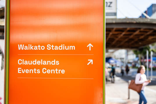 A person walks past a sign with directions to Waikato