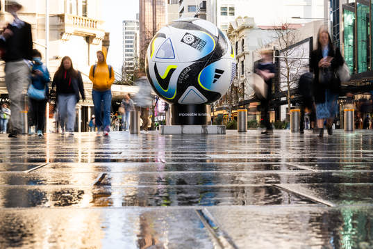 People walk past a replica of the official match ball