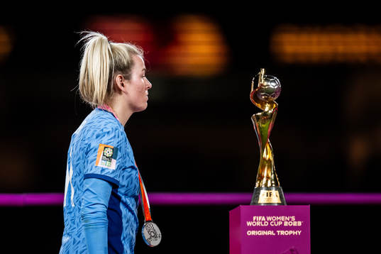 Lauren Hemp of England walks past the trophy