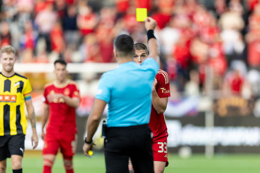 Slobodan Rubezic of Aberdeen is shown a yellow card by