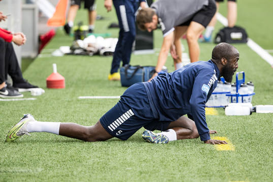 Utsiktens Ronald Mukiibi värmer upp innan fotbollsmatchen