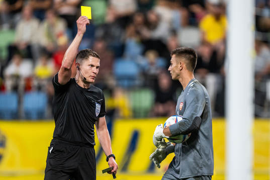 Referee David Dickinson shows the yellow card to goalkeeper