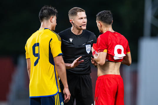 Jusef Erabi of Sweden, referee David Dickinson, and Ivan