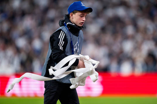 A ball boy picking up trash from the pitch