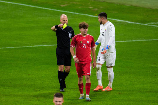 Ioan-Calin Revenco of Moldova receives a yellow card from