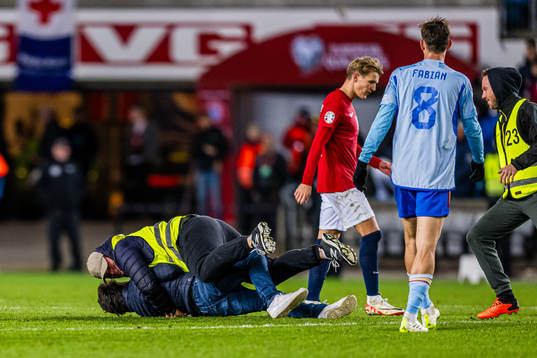 A steward is taking care of a pitch invader