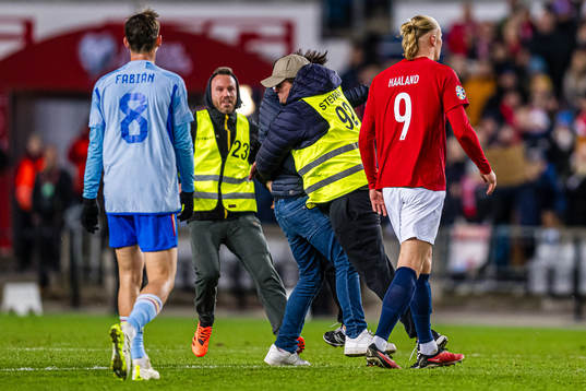 A steward is taking care of a pitch invader