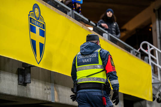 A security guard walks past the logo of the Swedish