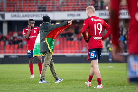 En åskådare kliver in på planen med en flagga