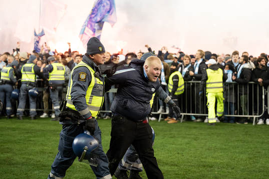 En supporter tas om hand av ordningsvakter innan