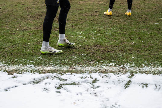 Feet with football boots and snow