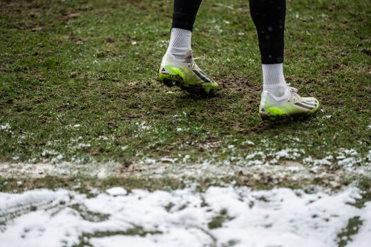 Feet with football boots and snow