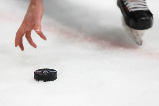 En domare är påväg att plocka upp en puck från isen