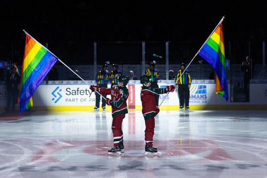 Maskotar med pride flaggor innan ishockeymatchen i SHL