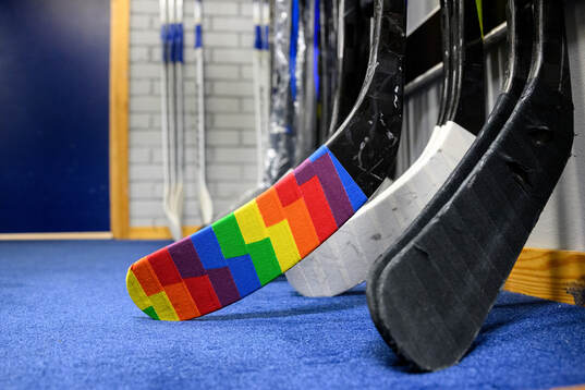 En klubbe tejpad med tejp i regnbågsfärger i HV71s