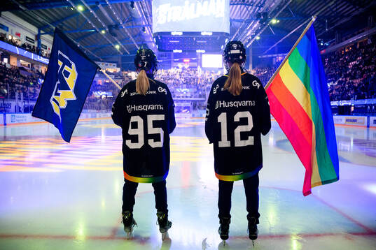 Flaggbärare med HV71s flagga och prideflaggan