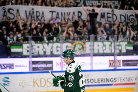 Färjestads Per Åslund med tifo i bakgrunden där det