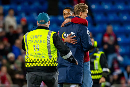 A pitch invader hugs Martin Ødegaard of Norway