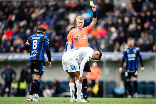 Domare Adam Ladebäck delar ut ett gult kort till Halmstads