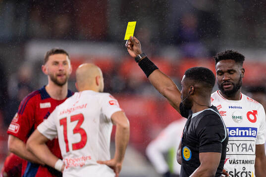Domare Fredrik Oppong delar ut ett gult kort