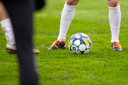 Fotboll och fotbollskor på gräsplan
