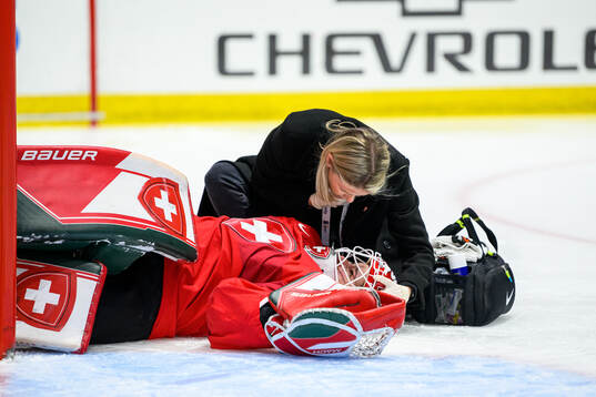 Goaltender Andrea Braendli of Switzerland receives medical