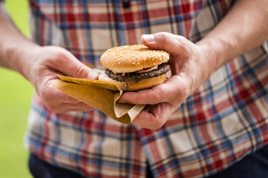 En person håller upp en hamburgare innan fotbollsmatchen i