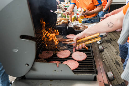 Personer grillar hamburgare och korv innan fotbollsmatchen