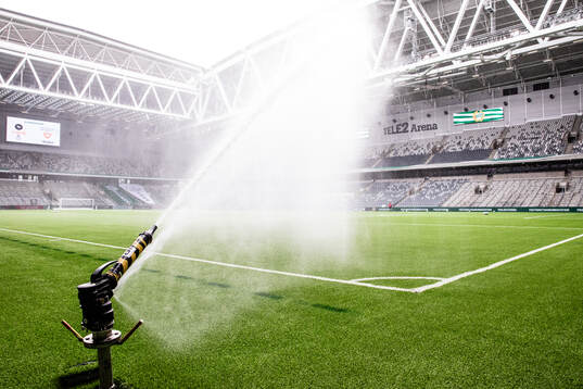 En vattenspridare vattnar konstgräset på Tele2 Arena