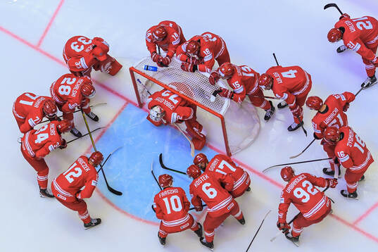 Players gather around goaltender David Zabolotny of Poland
