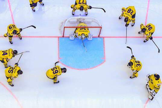 Players of Sweden gather around goaltender Filip Gustavsson